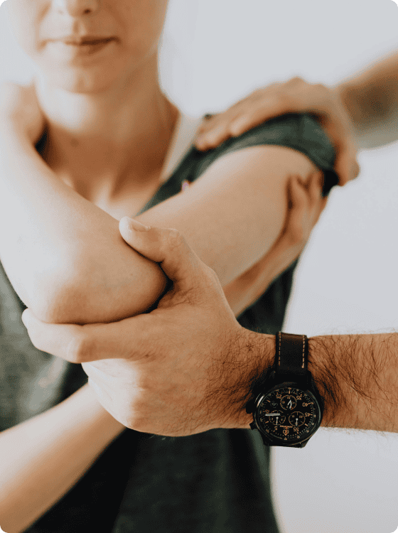 A person wearing a dark watch assists another by holding their elbow, possibly during a physical therapy or exercise session, showcasing the importance of primary care in rehabilitation.